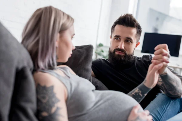 Tattooed pregnant girlfriend and boyfriend holding hands at home — Stock Photo