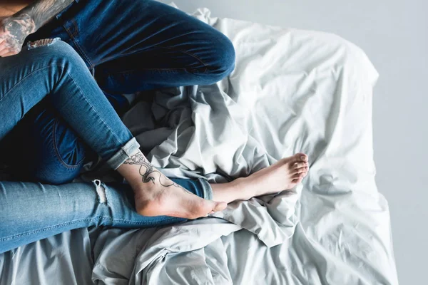 Cropped image of tattooed couple on bed at home — Stock Photo