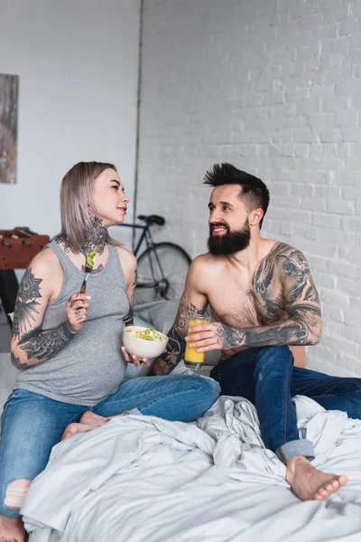 Embarazada tatuado novia comer ensalada en casa - foto de stock