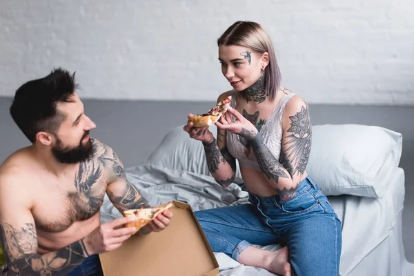 Glückliches tätowiertes Paar, das zu Hause Pizza isst — Stockfoto