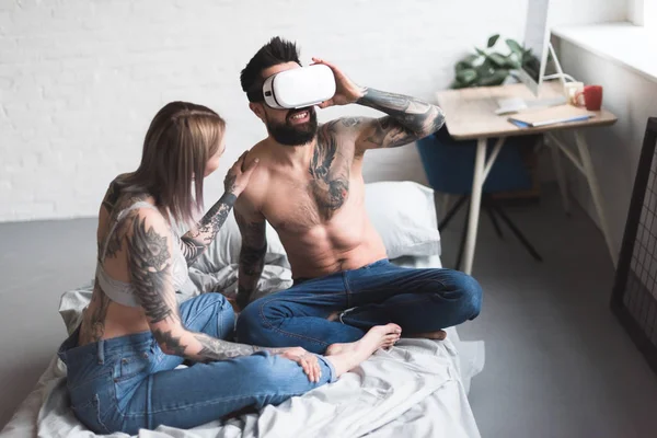 Татуированный парень, использующий гарнитуру виртуальной реальности дома — стоковое фото