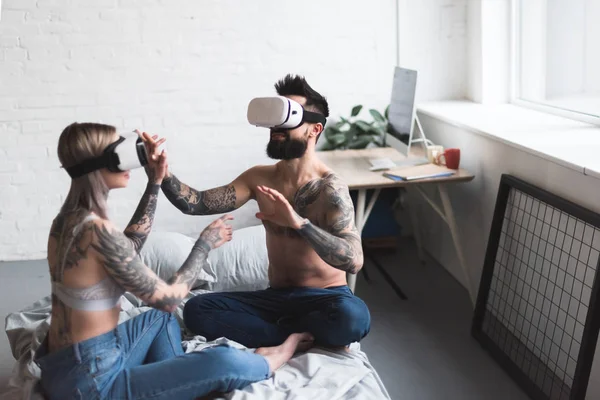 Tattooed couple using vr headsets on bed at home — Stock Photo