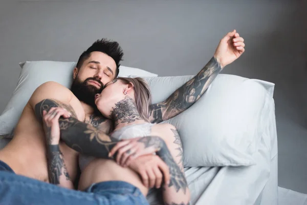 Татуированная пара без рубашки спит на кровати — стоковое фото