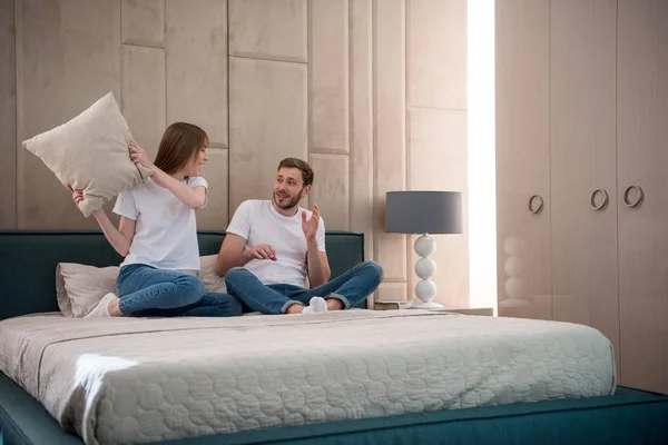 Woman going to hit her boyfriend by pillow in cozy bedroom — Stock Photo