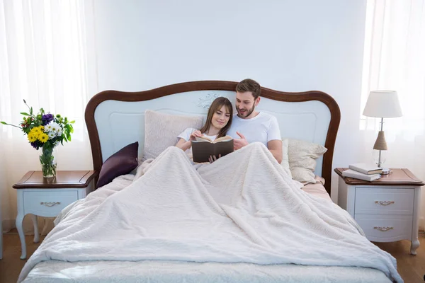 Vista frontal do livro de leitura de casal no quarto moderno acolhedor — Fotografia de Stock