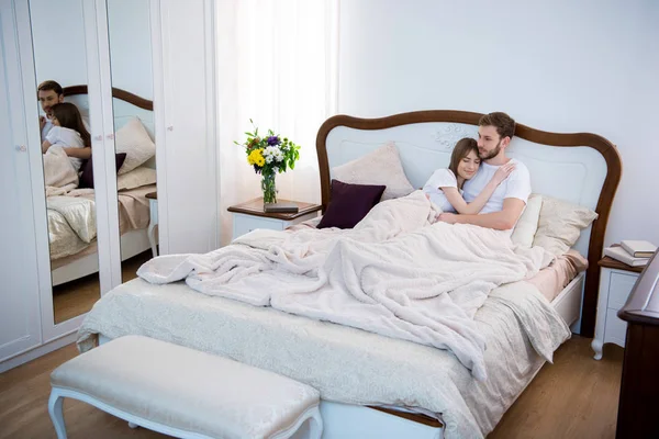 Casal deitado na cama no aconchegante quarto moderno — Fotografia de Stock