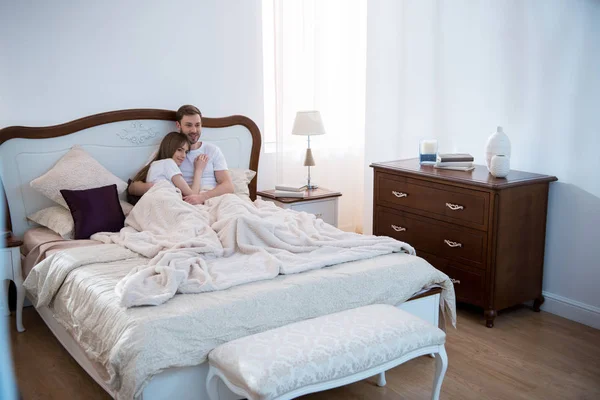 Mujer joven acostada en el pecho de su novio en el dormitorio con interior moderno - foto de stock