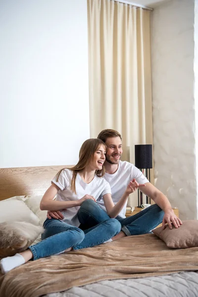 Giovane donna sorridente con fidanzato in camera da letto con design moderno — Foto stock