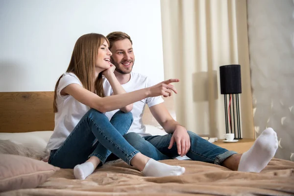 Jeune femme pointant du doigt son petit ami dans la chambre à coucher avec intérieur moderne — Photo de stock