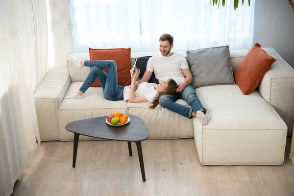 Donna che utilizza tablet digitale e sdraiata sulle ginocchia del suo fidanzato in moderno moderno — Foto stock