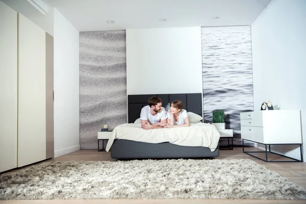 Jovem casal deitado no quarto com interior moderno — Fotografia de Stock