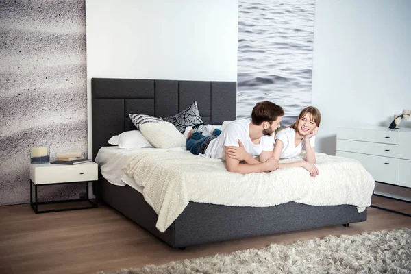 Jeune couple souriant couché dans une chambre avec un intérieur design — Photo de stock