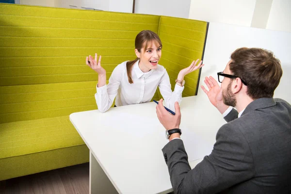 Dos colegas de negocios debatiendo y sentados a la mesa - foto de stock