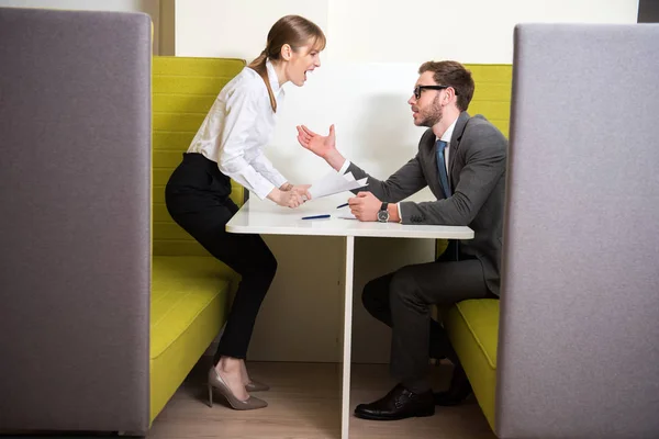 Colegas de negócios discutindo enquanto se sentam à mesa com papéis e canetas — Fotografia de Stock