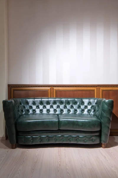 Green leather couch in front of wall with wooden decoration — Stock Photo