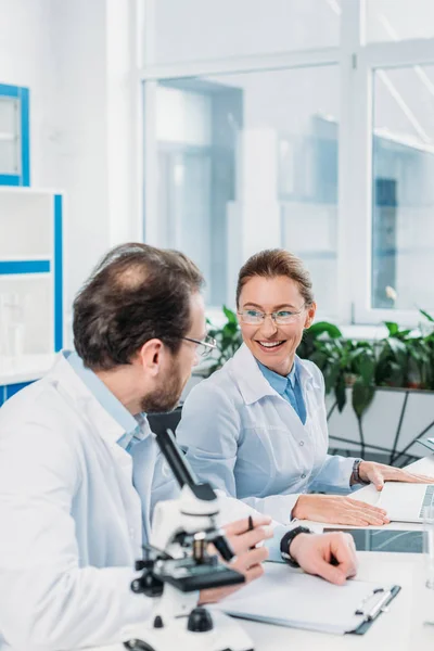 Wissenschaftler in weißen Kitteln arbeiten am Arbeitsplatz im Labor zusammen — Stockfoto