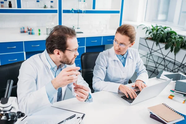 Ricercatori scientifici in camici bianchi che discutono il lavoro sul posto di lavoro in laboratorio — Foto stock