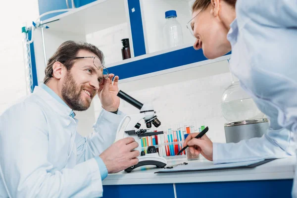 Scientific researchers in white coats and eyeglasses in laboratory — Stock Photo