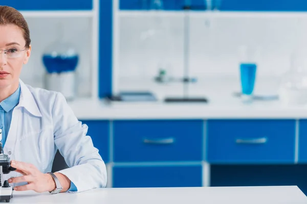 Partial view of female scientist in eyeglasses with microscope in laboratory — Stock Photo