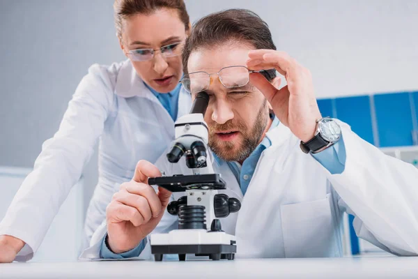 Scientists in white coats and eyeglasses working with reagent together in lab — Stock Photo