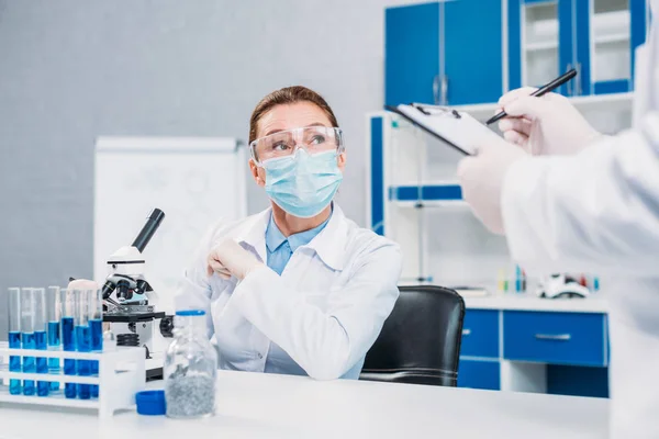 Visión parcial de los científicos en máscaras y gafas médicas que trabajan en la investigación científica en laboratorio - foto de stock