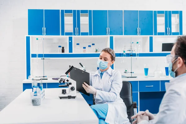 Частичный взгляд ученых в белых халатах на рабочем месте в лаборатории — стоковое фото