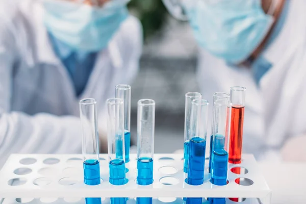 Selective focus of tubes with reagents and scientists in medical masks — Stock Photo