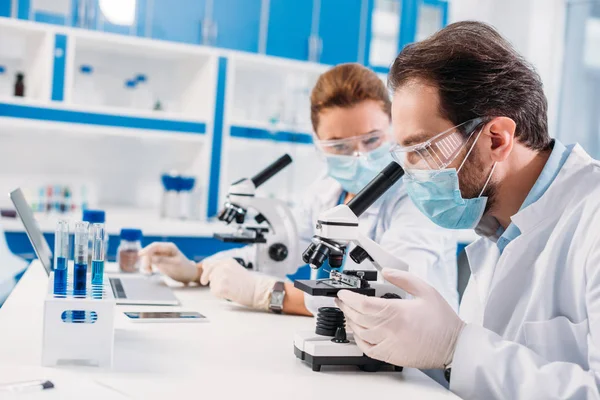 Selective focus of scientists in medical masks working in lab together — Stock Photo