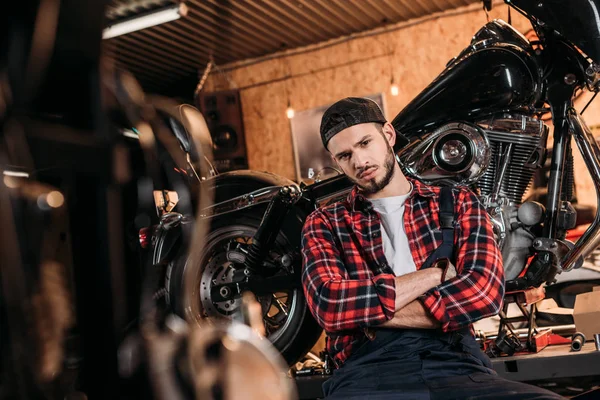 Beau travailleur de station de réparation de vélo assis devant la moto — Photo de stock