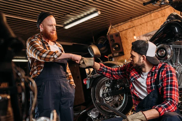 Mecânica bonito fazendo bro punho na garagem de reparação de motocicleta — Fotografia de Stock