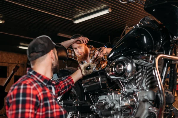 Handsome mechanics repairing motorcycle together at custom garage — Stock Photo