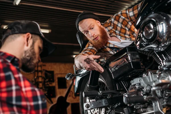 Professional mechanics repairing motorcycle together at garage — Stock Photo