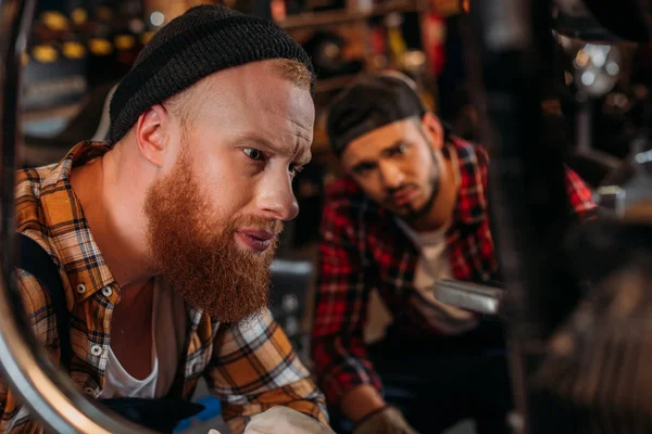 Handsome mechanics looking at motorcycle to repair at garage — Stock Photo
