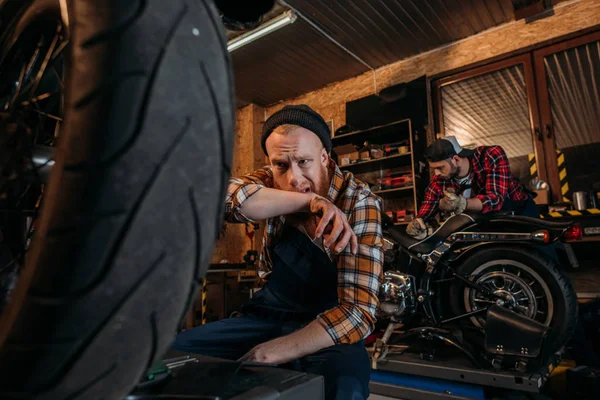 Exhausted mechanic wiping sweat after work at garage — Stock Photo