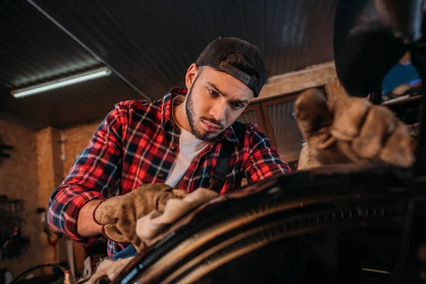 Close-up shot of bike repair station worker cleaning wheel at garage — Stock Photo