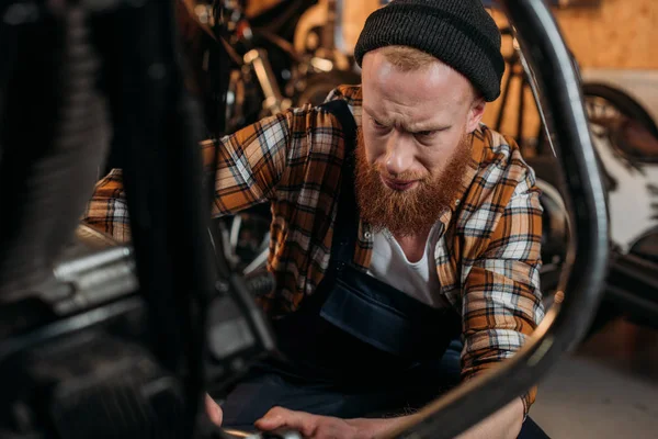 Концентрована ремонтна станція працівник фіксує мотоцикл в гаражі — стокове фото