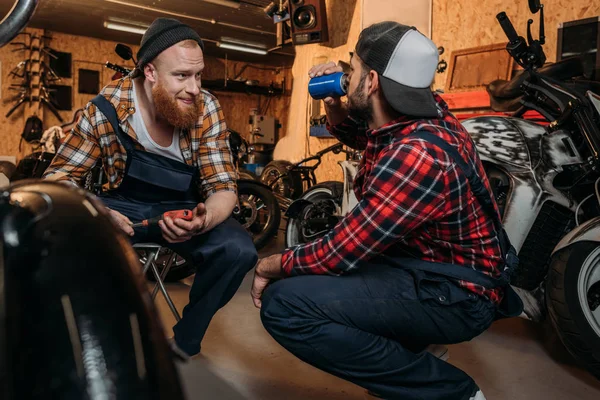 Young mechanics having break in work at garage — Stock Photo