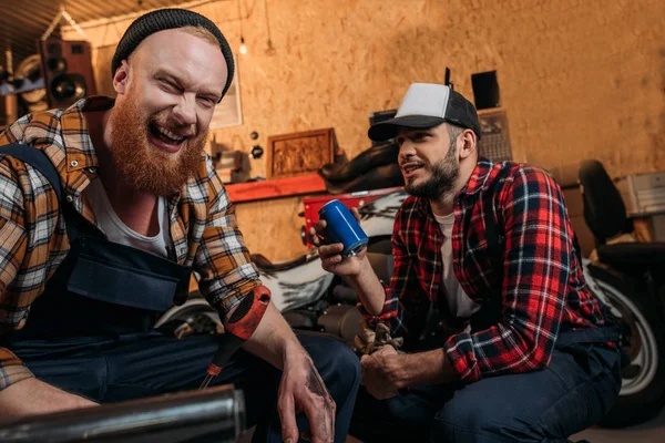 Laughing young mechanics having break in work at garage — Stock Photo