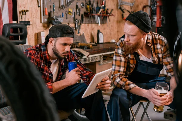 Belle mécanique avec tablette boire de la bière au garage — Photo de stock