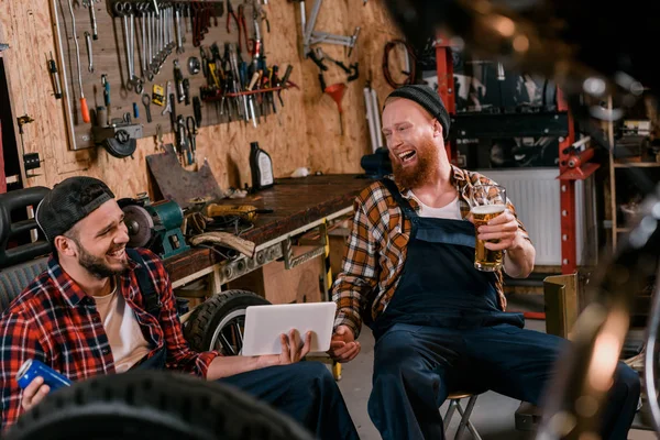 Механіка сміху з планшетом і пивом в гаражі — стокове фото