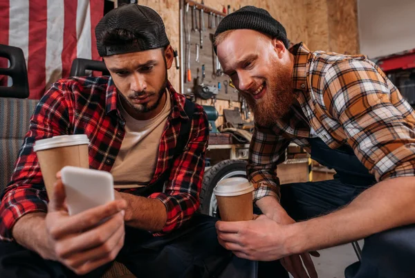 Handsome mechanics with coffee to go taking selfie at garage — Stock Photo