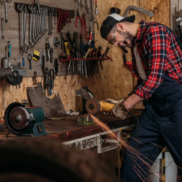 Screaming bike repair station worker using electric circular saw at garage — Stock Photo