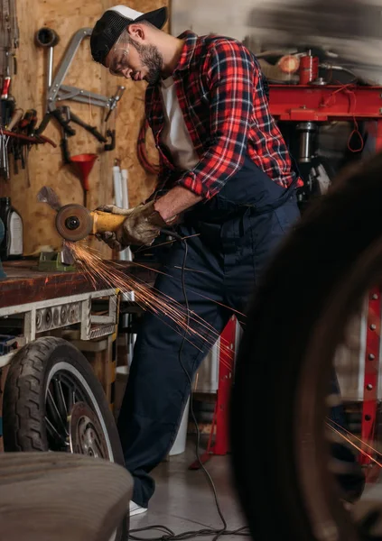 Trabalhador bonito da estação de reparo da bicicleta usando serra circular elétrica na garagem — Stock Photo