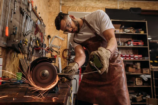 Gutaussehender Werkstattarbeiter mit Schleifmaschine in Garage — Stockfoto