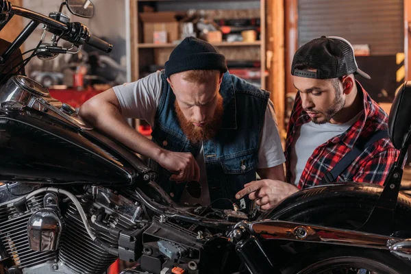 Працівник ремонту розмовляє з клієнтом і показує проблему на мотоциклі — стокове фото