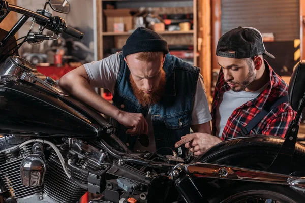 Trabajador de reparación hablando con el cliente y mostrando problema en motocicleta - foto de stock