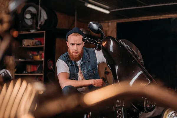 Portrait of handsome young man on bike at garage — Stock Photo