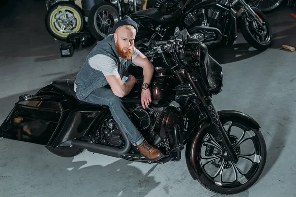 Vue grand angle de beau jeune homme à vélo au garage et regardant la caméra — Photo de stock