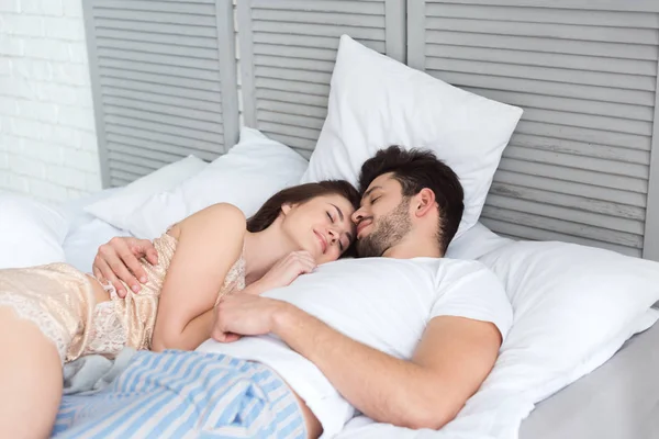 Jeune couple en pyjama dormant au lit ensemble — Photo de stock