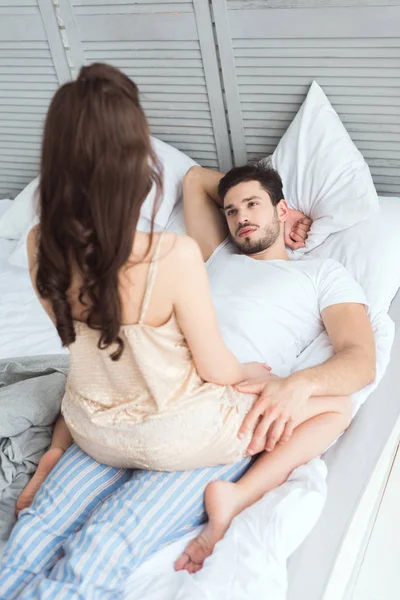 Partial view of young man looking at girlfriend in pajamas on bed — Stock Photo